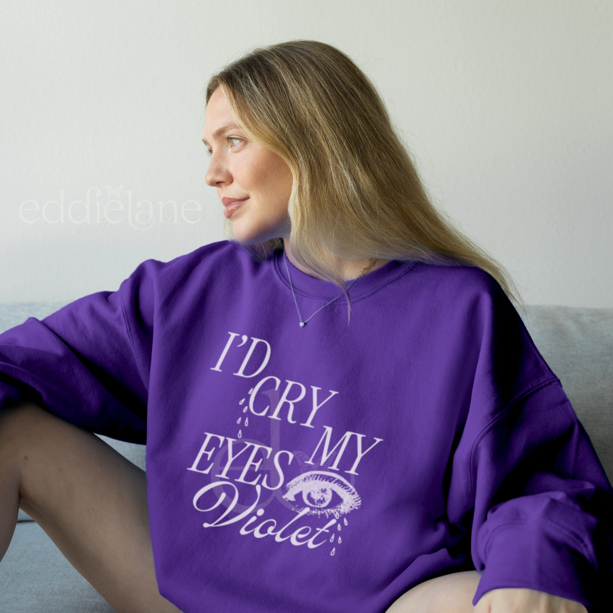 Woman wearing a purple sweatshirt with the text "i'd cry my eyes violet" with a graphic of an eye crying