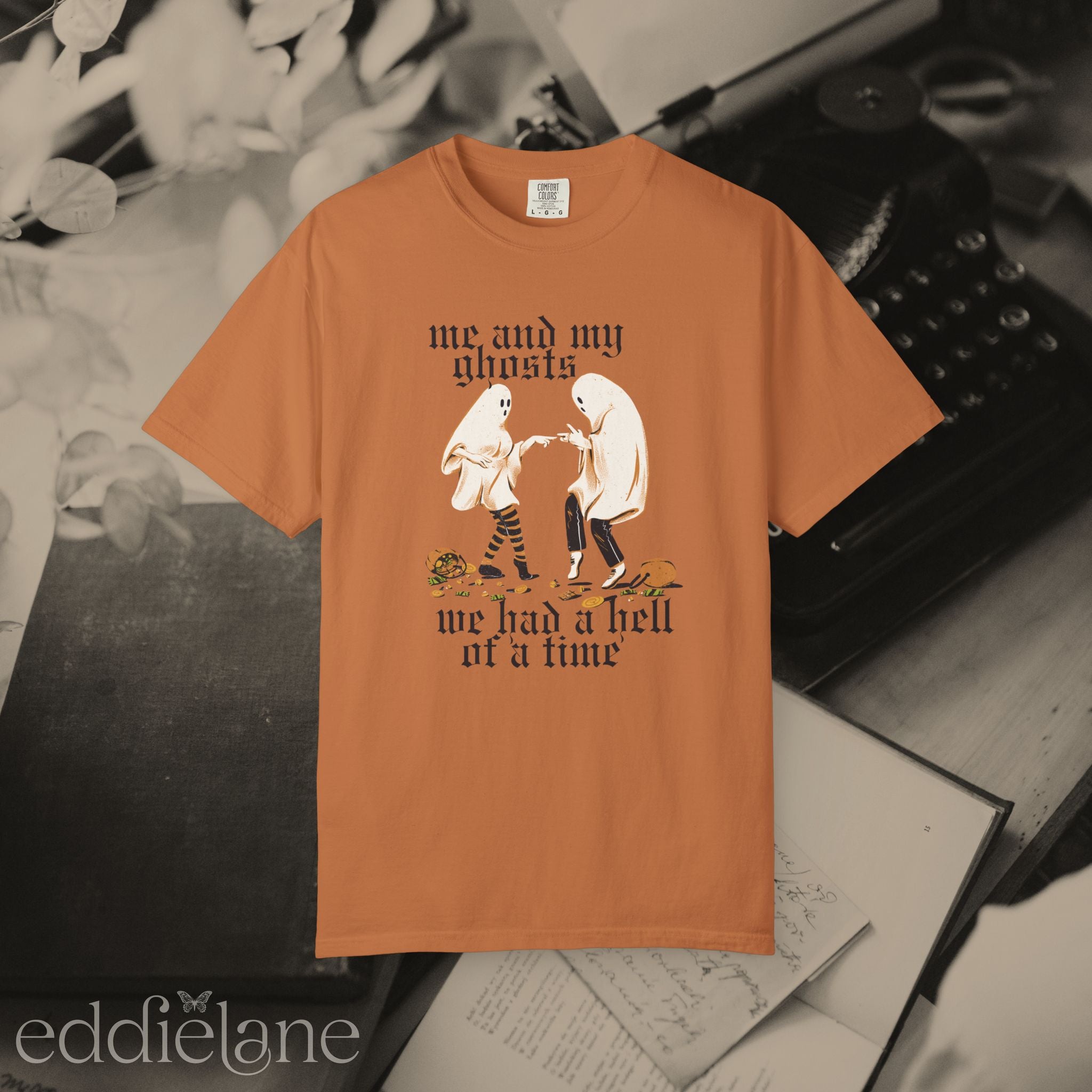 an orange halloween graphic tee with a vintage aesthetic, featuring a graphic of two ghosts and the words "me and my ghosts we had a hell of a time"