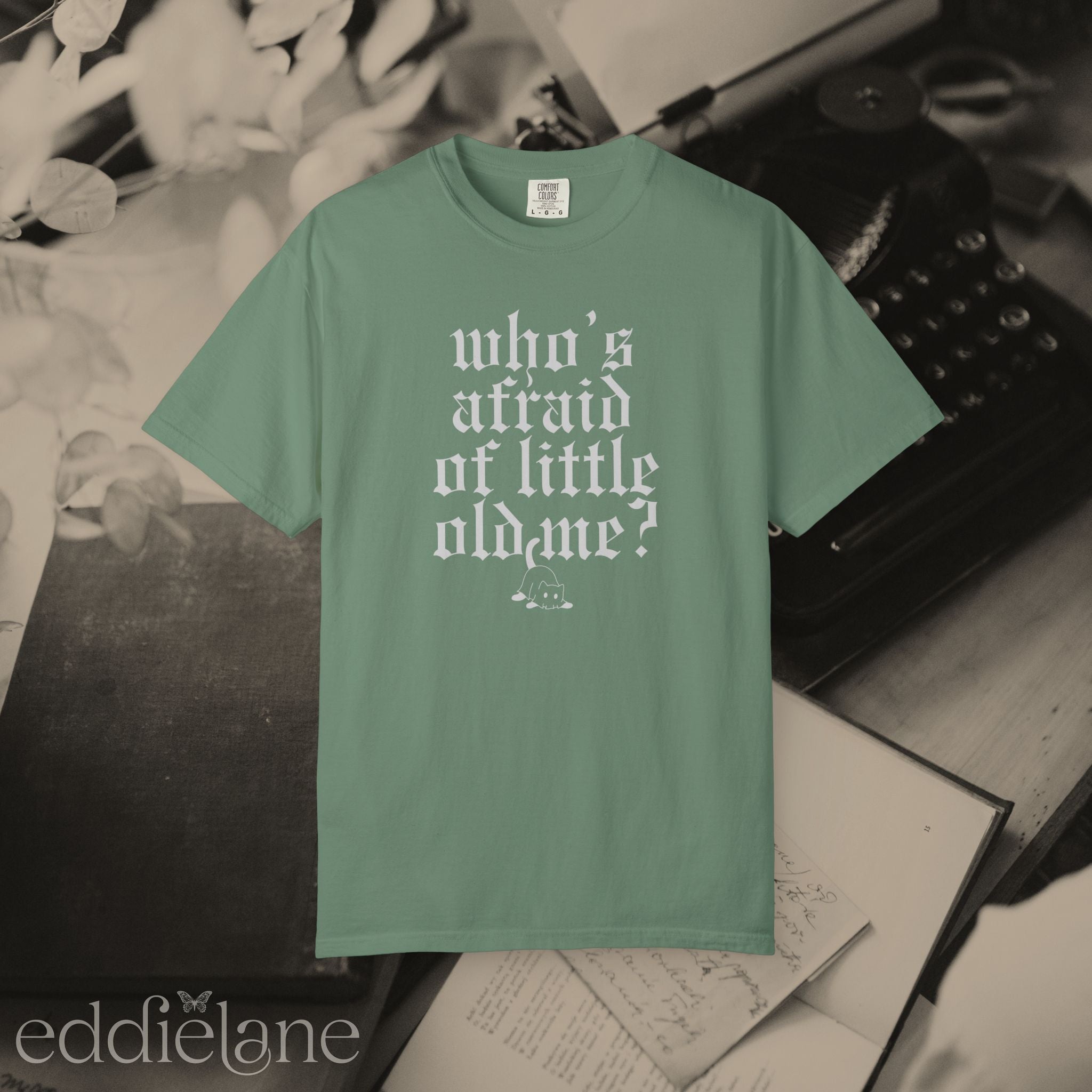 a green comfort colors t-shirt that says "who's afraid of little old me" with a graphic of a cat wearing a ghost costume