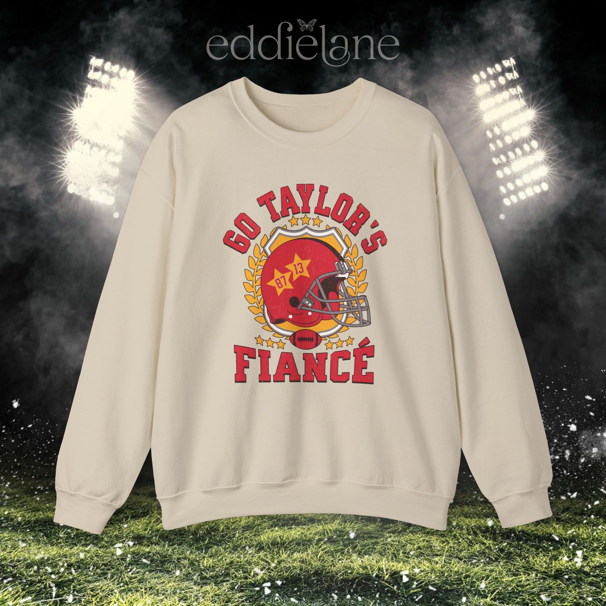 a sand crewneck sweatshirt with a vintage football helmet design and text that says "go taylor's fiance"