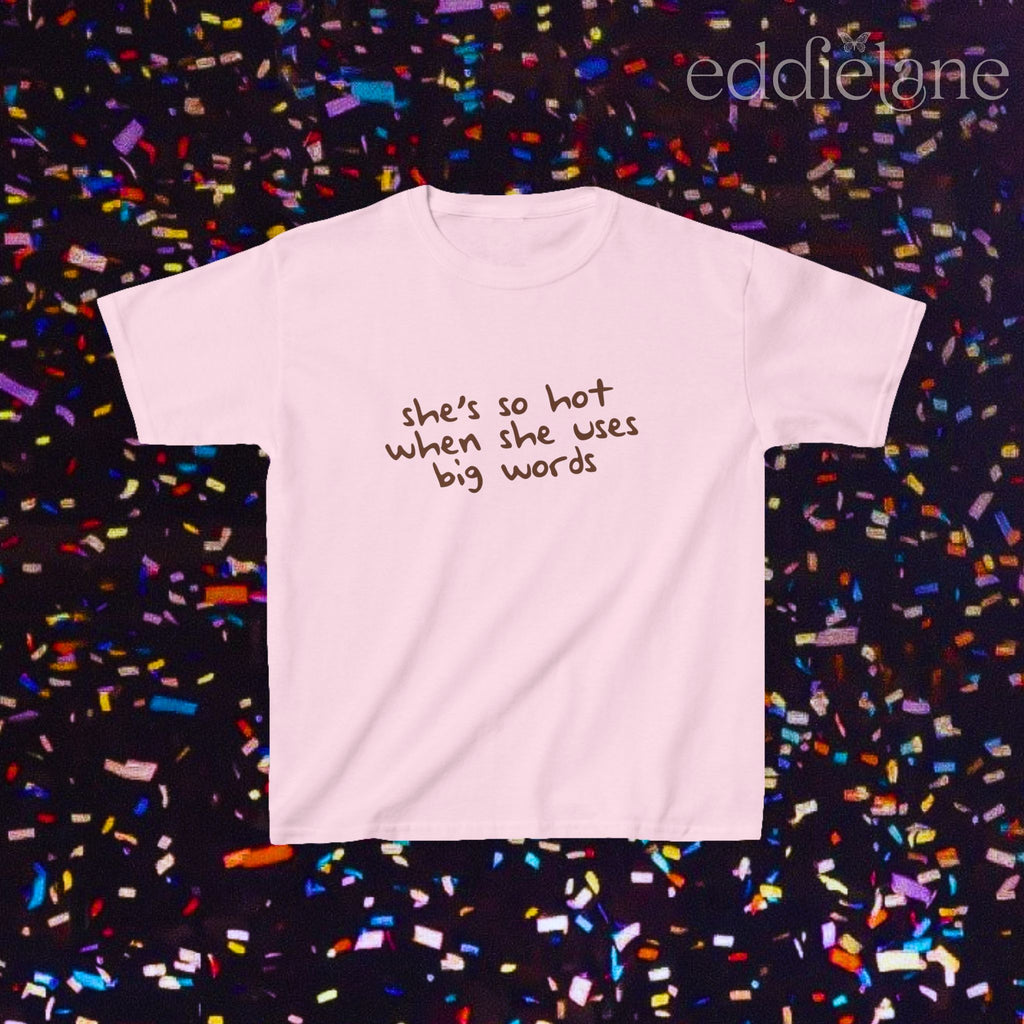 a light pink baby tee that says "she's so hot when she uses big words"