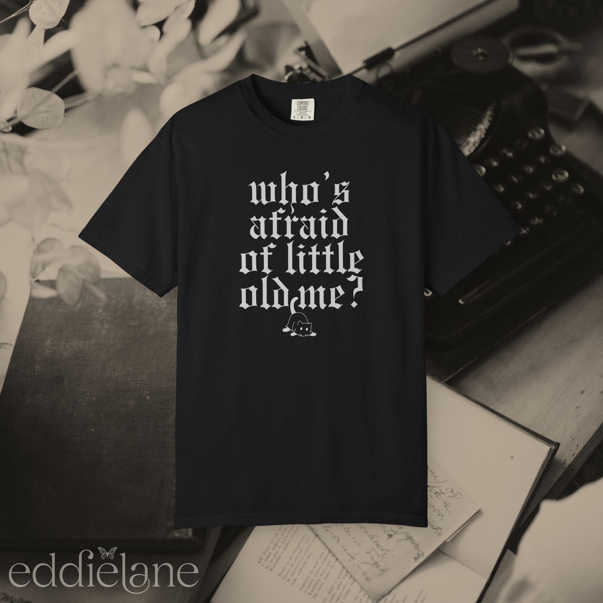 a black comfort colors t-shirt that says "who's afraid of little old me" with a graphic of a cat wearing a ghost costume