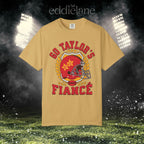 a gold t-shirt with a vintage football helmet design and text that says "go taylor's fiance"
