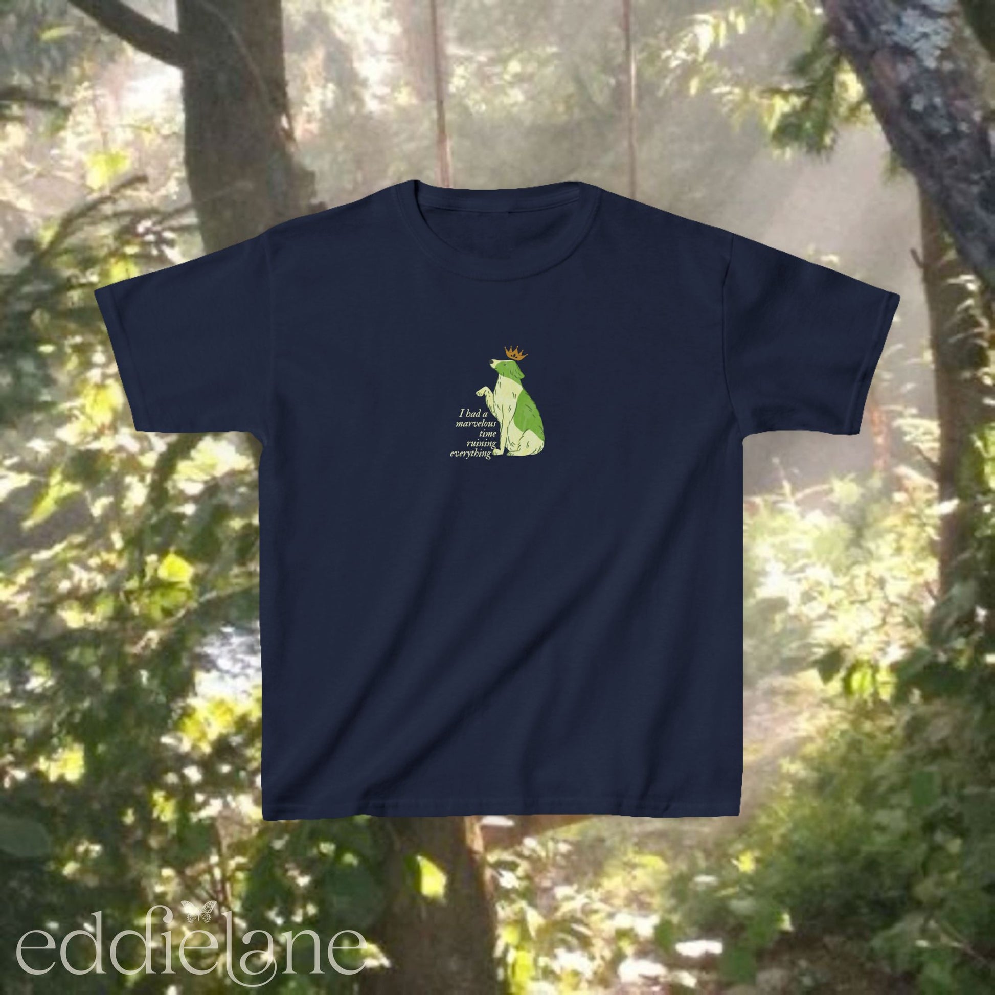 A navy baby tee with a graphic of a key-lime green dog wearing a crown and the words "i had a marvelous time ruining everything". Inspired by the song the last great american dynatsy from folklore by taylor swift.