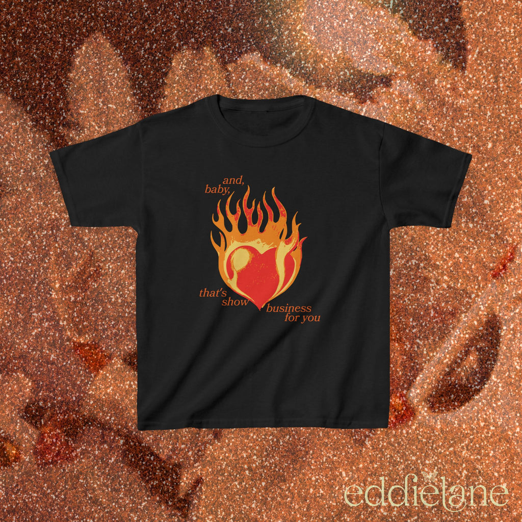 a black baby tee with a graphic of a heart on fire and the words "and, baby, that's show business for you"