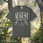 A minimalistic gray graphic tee that says 'August Sailing Club' with a sketch design of sailboats on a beach. 