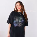 Woman wearing an oversized black t-shirt with the words "but now the sky is opalite" and a colorful galaxy design 