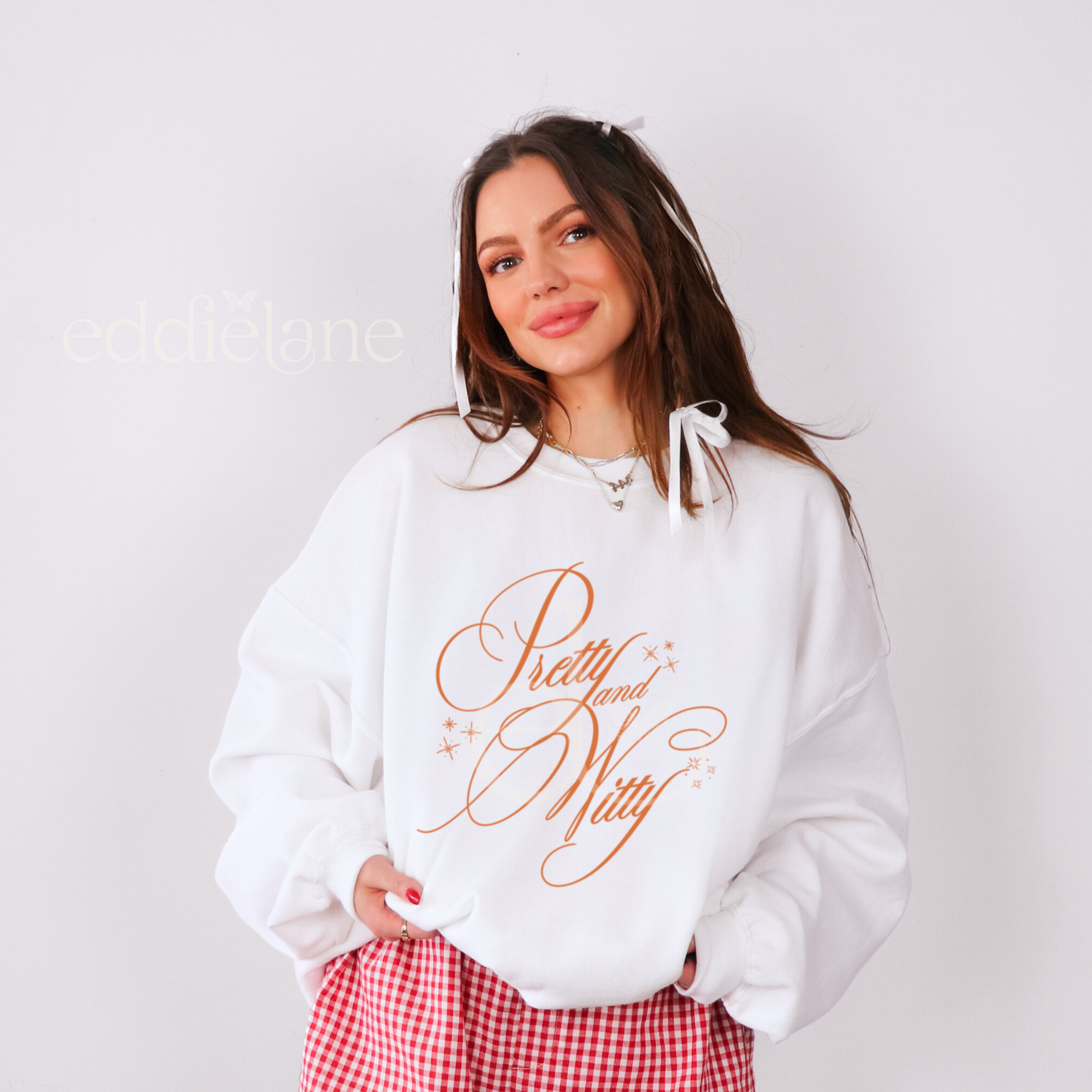woman wearing a white sweatshirt with the words "pretty and witty" written in orange in a beautiful script font