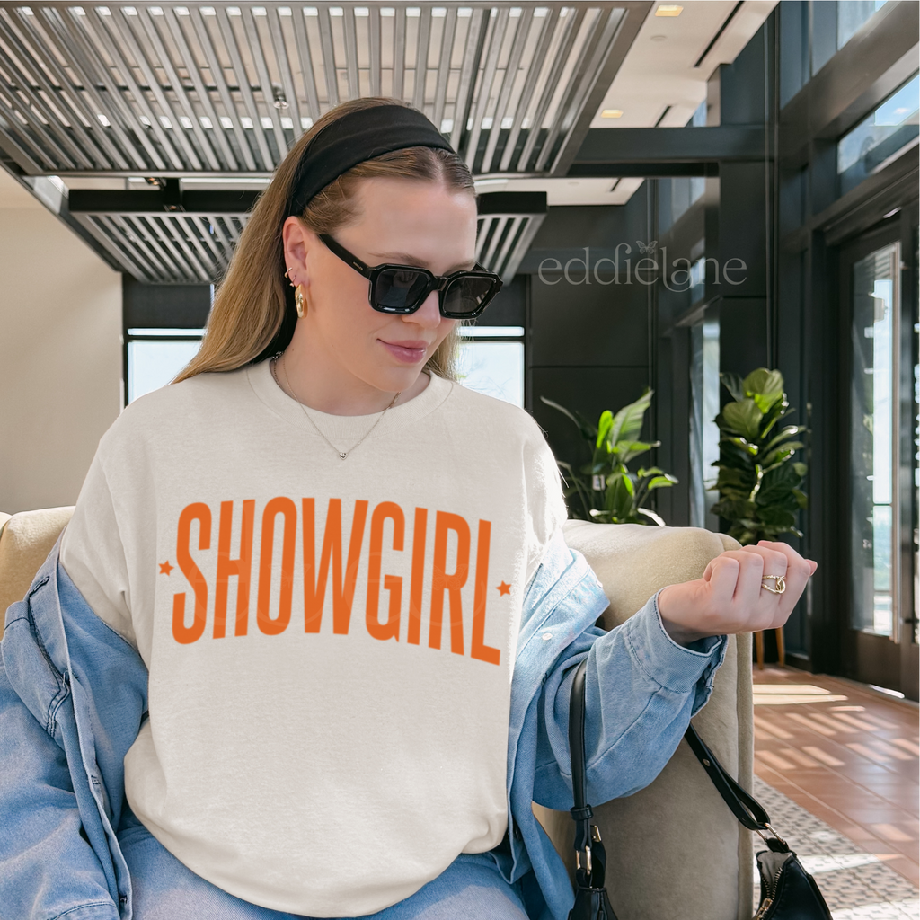 woman wearing an ivory comfort colors graphic tee that says 'SHOWGIRL'

ivory showgirl title tee