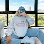 Woman wearing an ash gray crewneck sweatshirt that says 'it's Actually Romantic' 