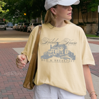 Girl wearing a yellow graphic t-shirt with 'Holiday House Bed & Breakfast' design, banana comfort colors shirt