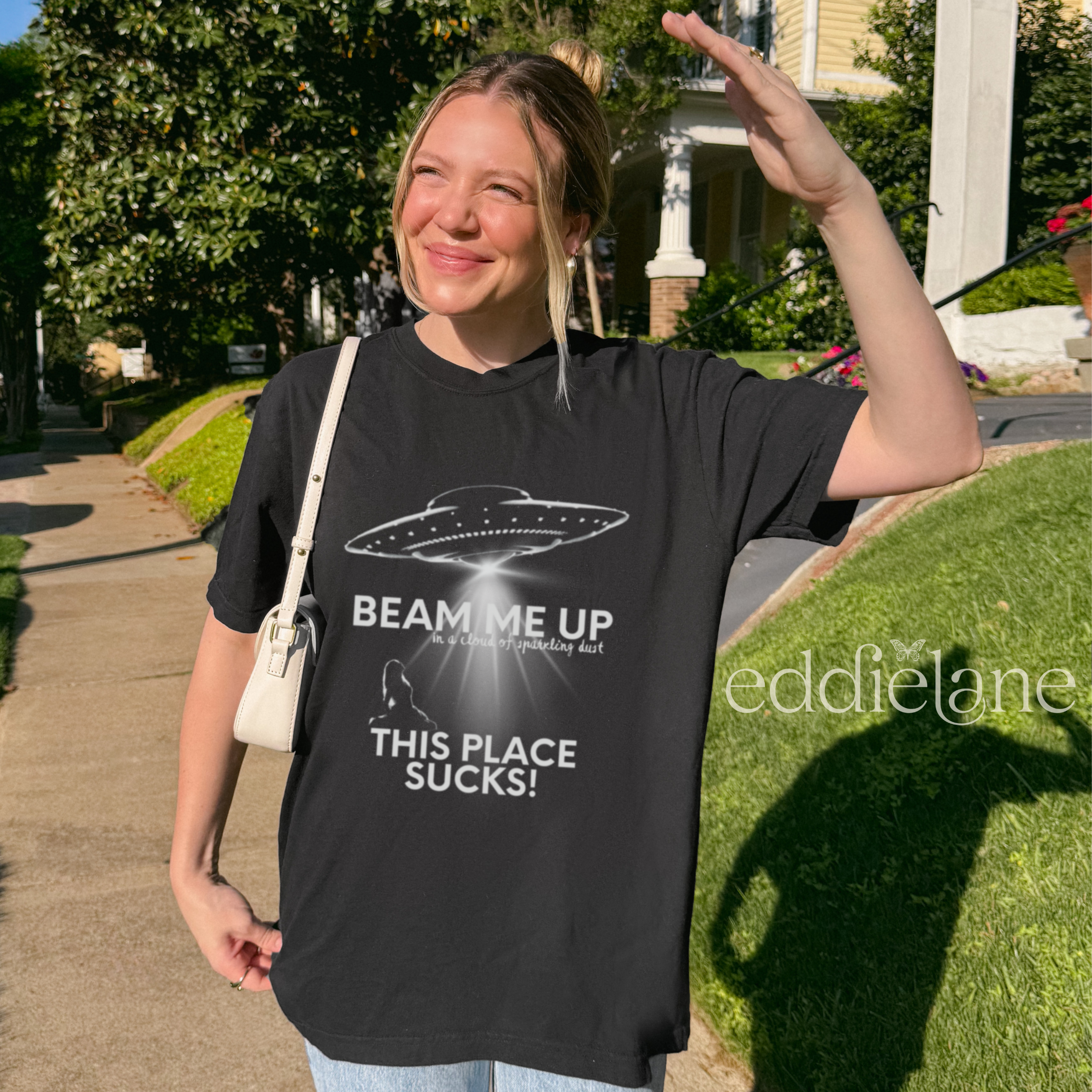 woman wearing an oversized black tshirt with a graphic of a UFO and the words beam me up this place sucks!