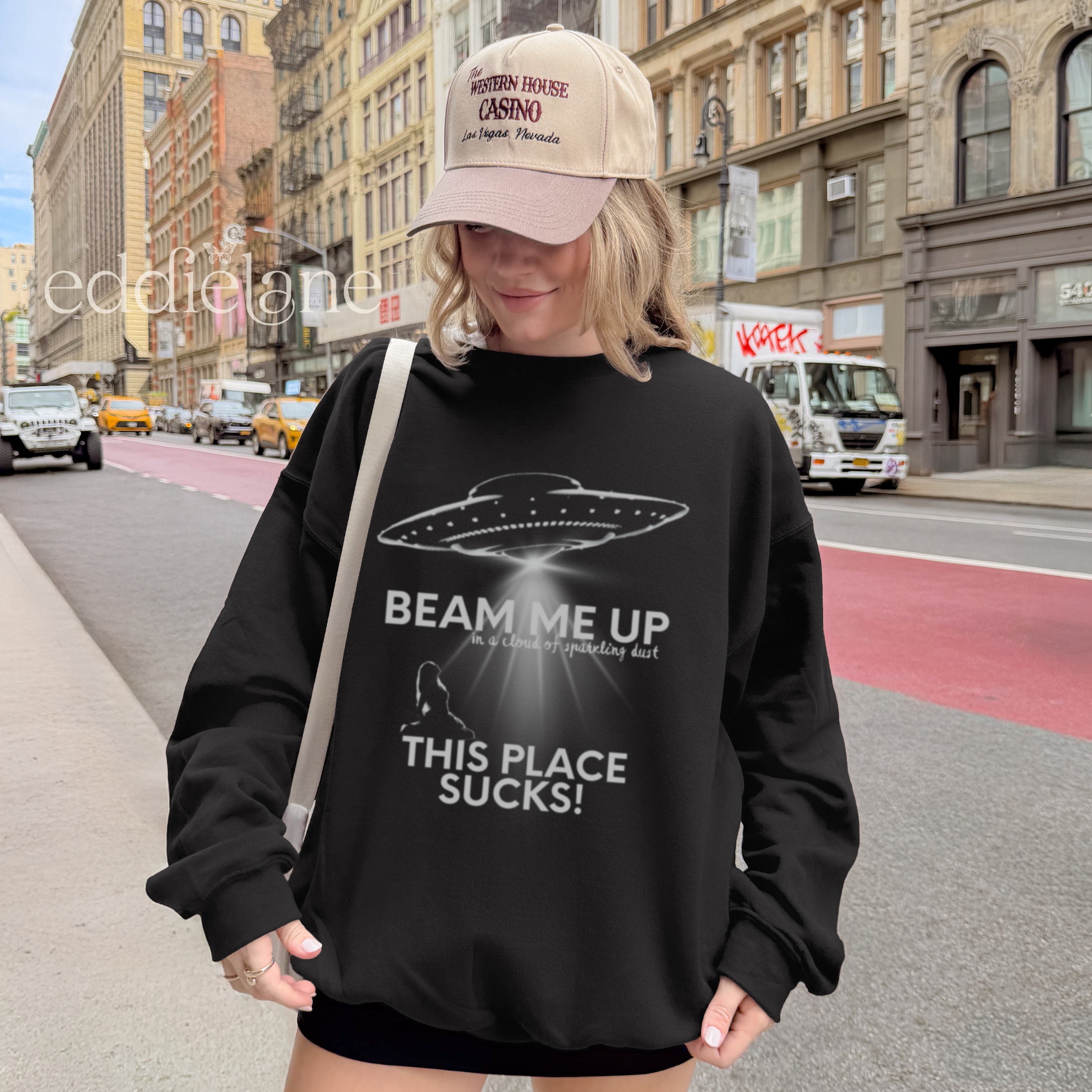 woman wearing a black sweatshirt with a graphic of a UFO and the words beam me up this place sucks!