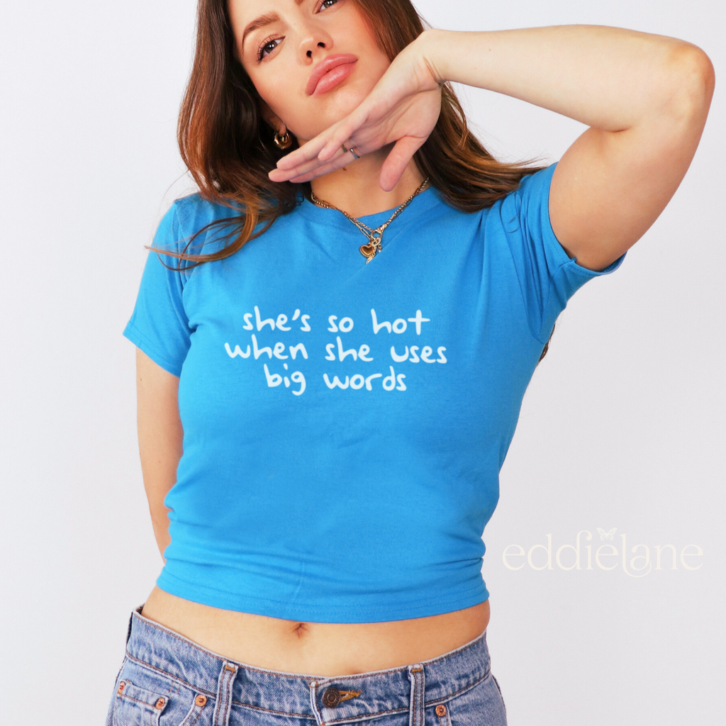 woman wearing a blue baby tee that says "she's so hot when she uses big words"