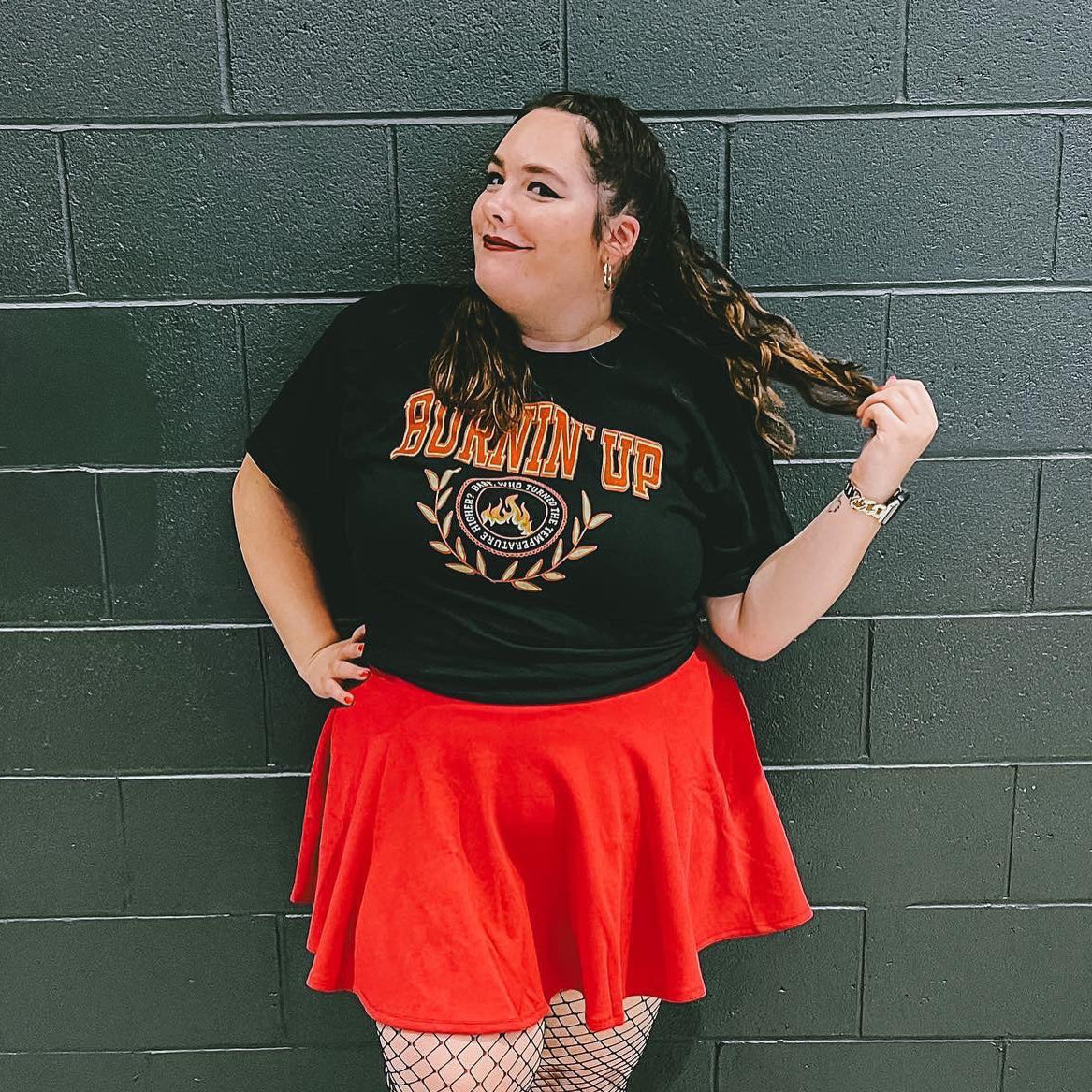 Woman wearing a black collegiate-style t-shirt that says "burnin up" 