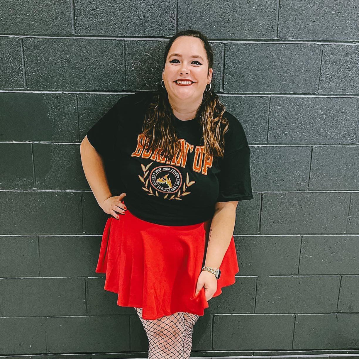 Woman wearing a black collegiate-style t-shirt that says "burnin up"