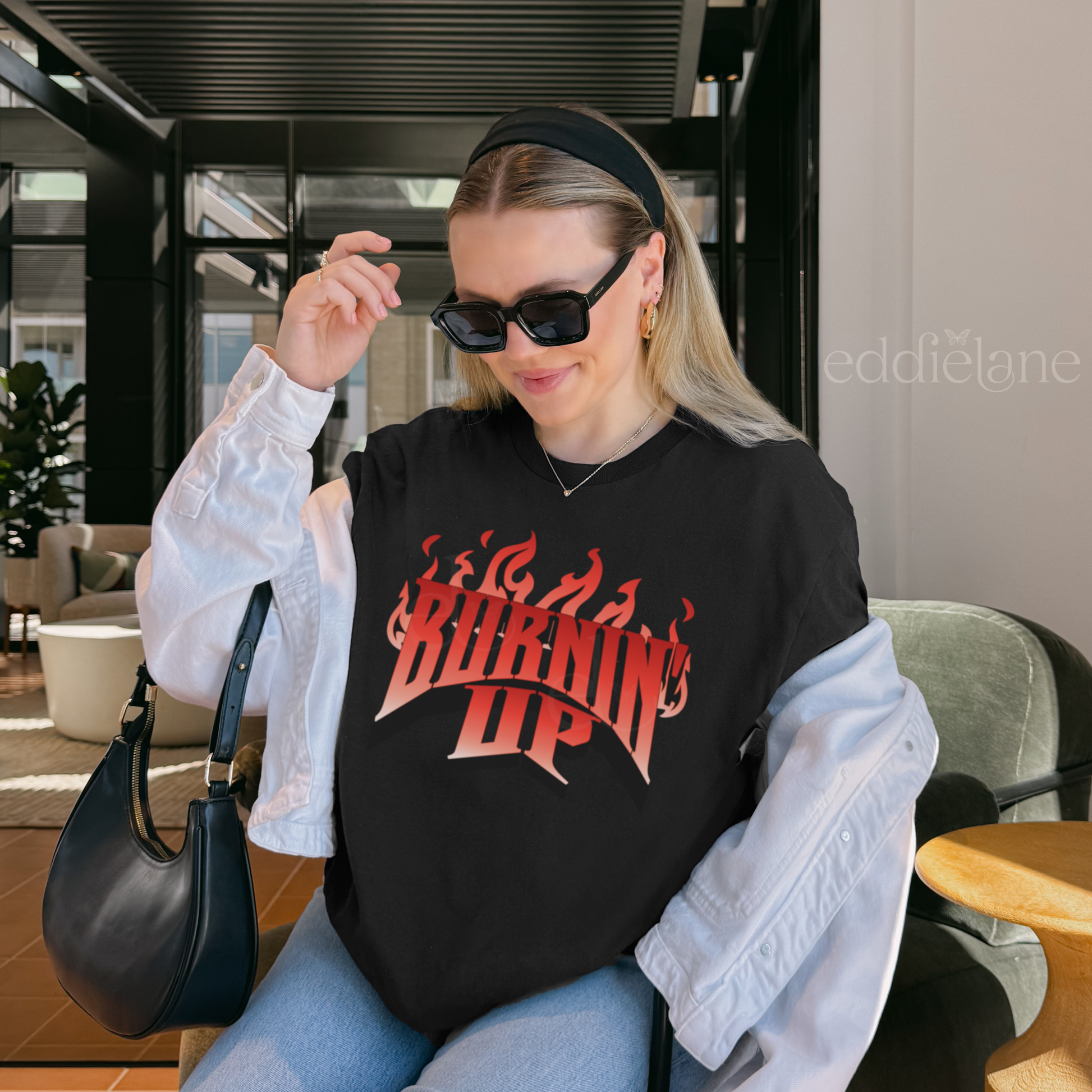 Woman wearing a black t-shirt with red and white graphic design that says "BURNIN' UP" in front of flames inspired by the Jonas Brothers.