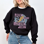 Woman wearing a black sweatshirt with the words "dancing through the lightning strikes" and a colorful disco ball and lightning bolt design