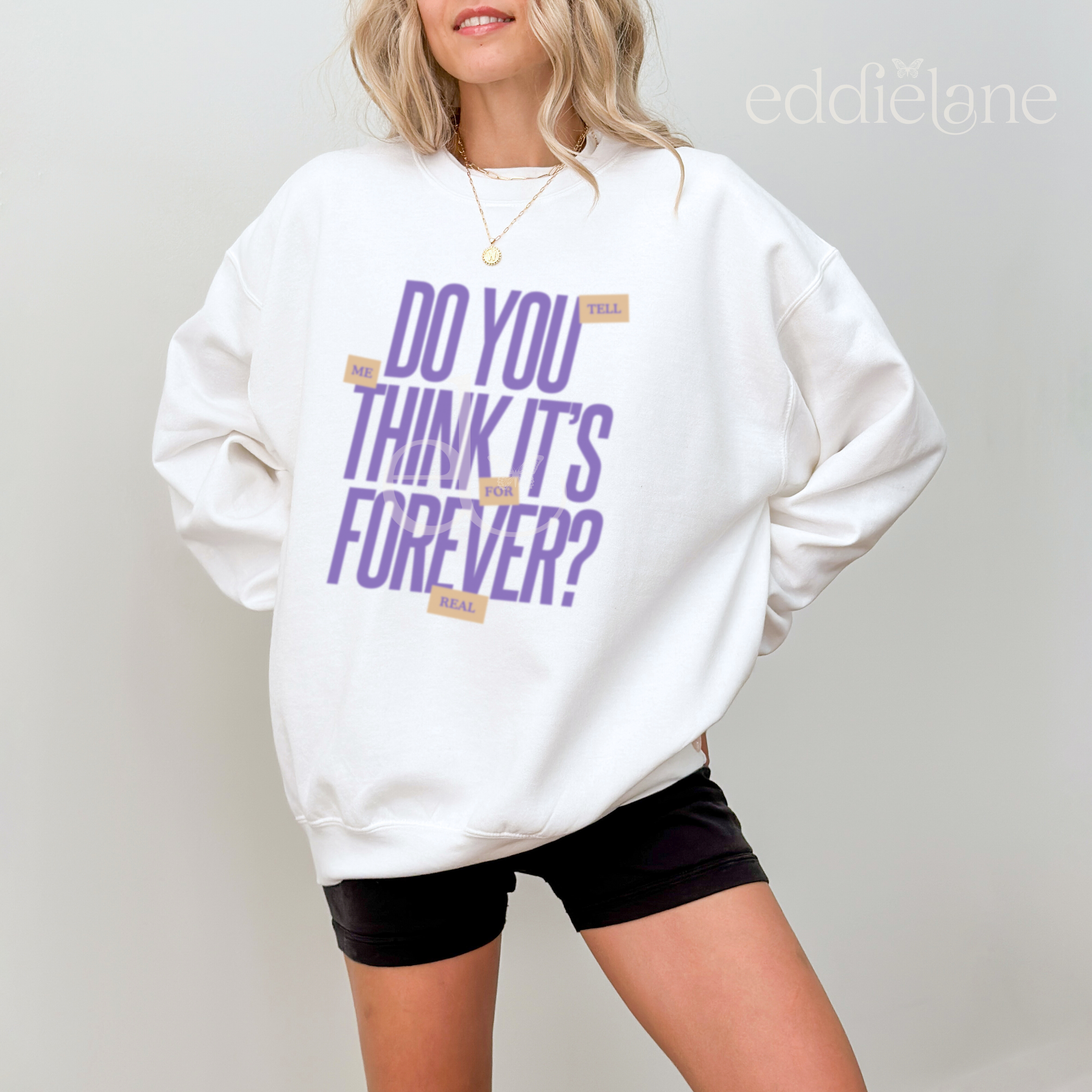 Woman wearing a white sweatshirt with purple text that says "do you think it's forever"