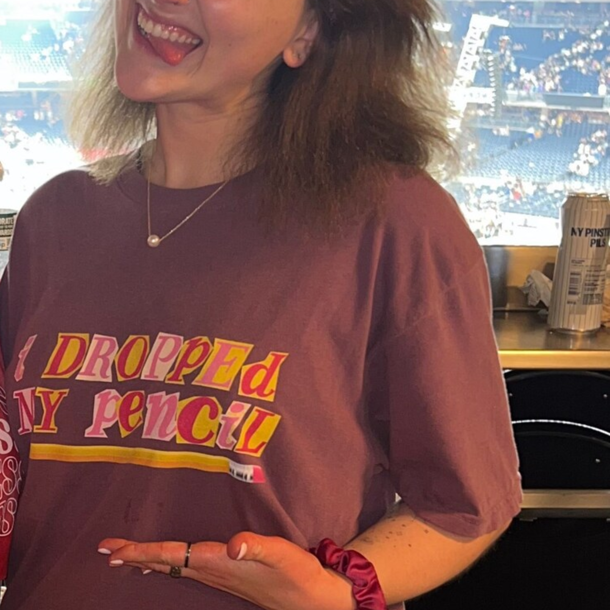 Woman wearing an oversized berry-colored t-shirt that says "i dropped my pencil" 