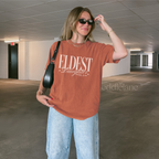 woman wearing an orange t-shirt that says "eldest daughter social club"