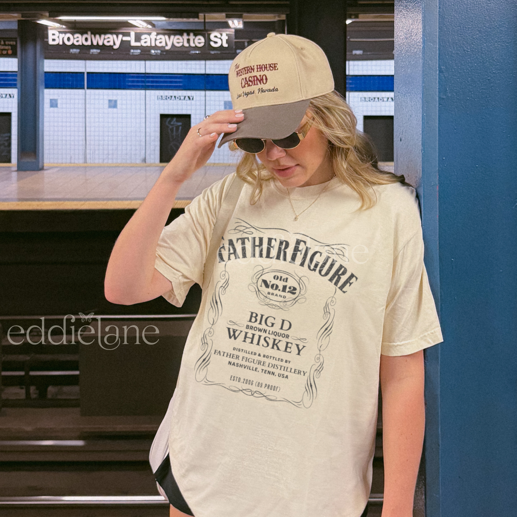 Woman wearing a 'Father Figure Whiskey' graphic t-shirt 