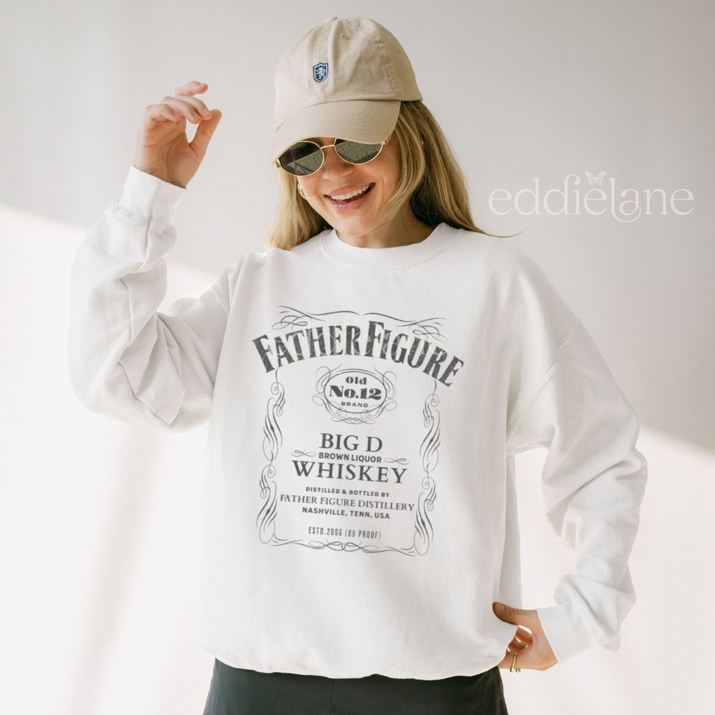 Person wearing a white sweatshirt with a graphic of 'Father Figure Whiskey' 