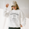 Person wearing a white sweatshirt with a graphic of 'Father Figure Whiskey' 
