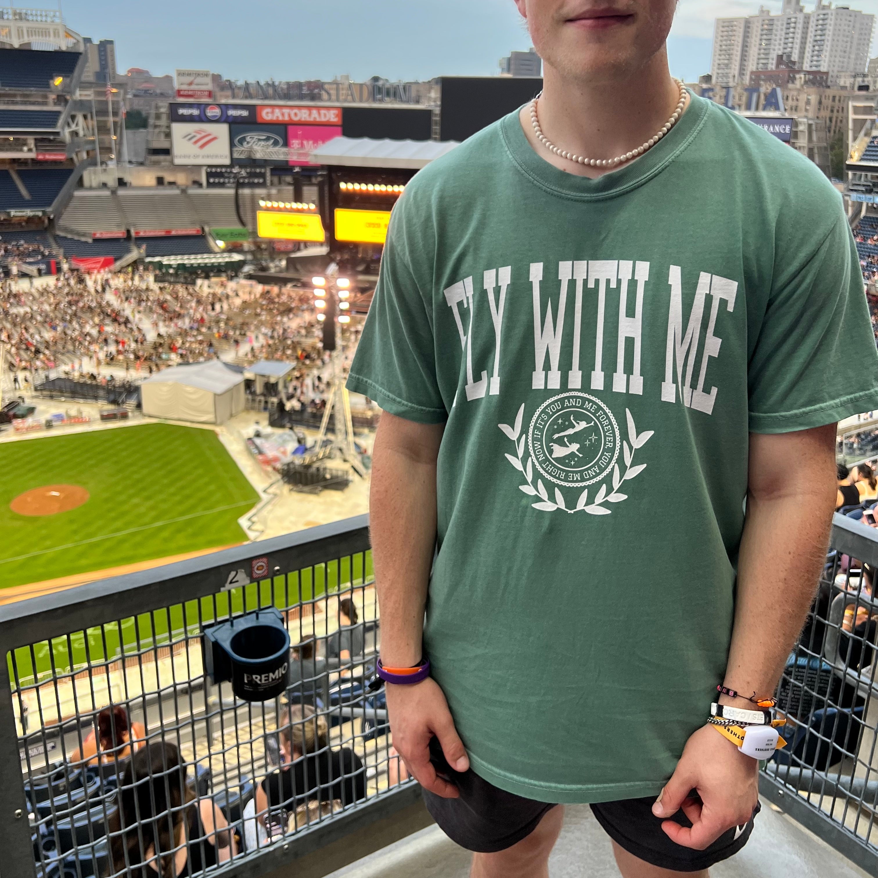 Man wearing a green 'Fly With Me' collegiate t-shirt 