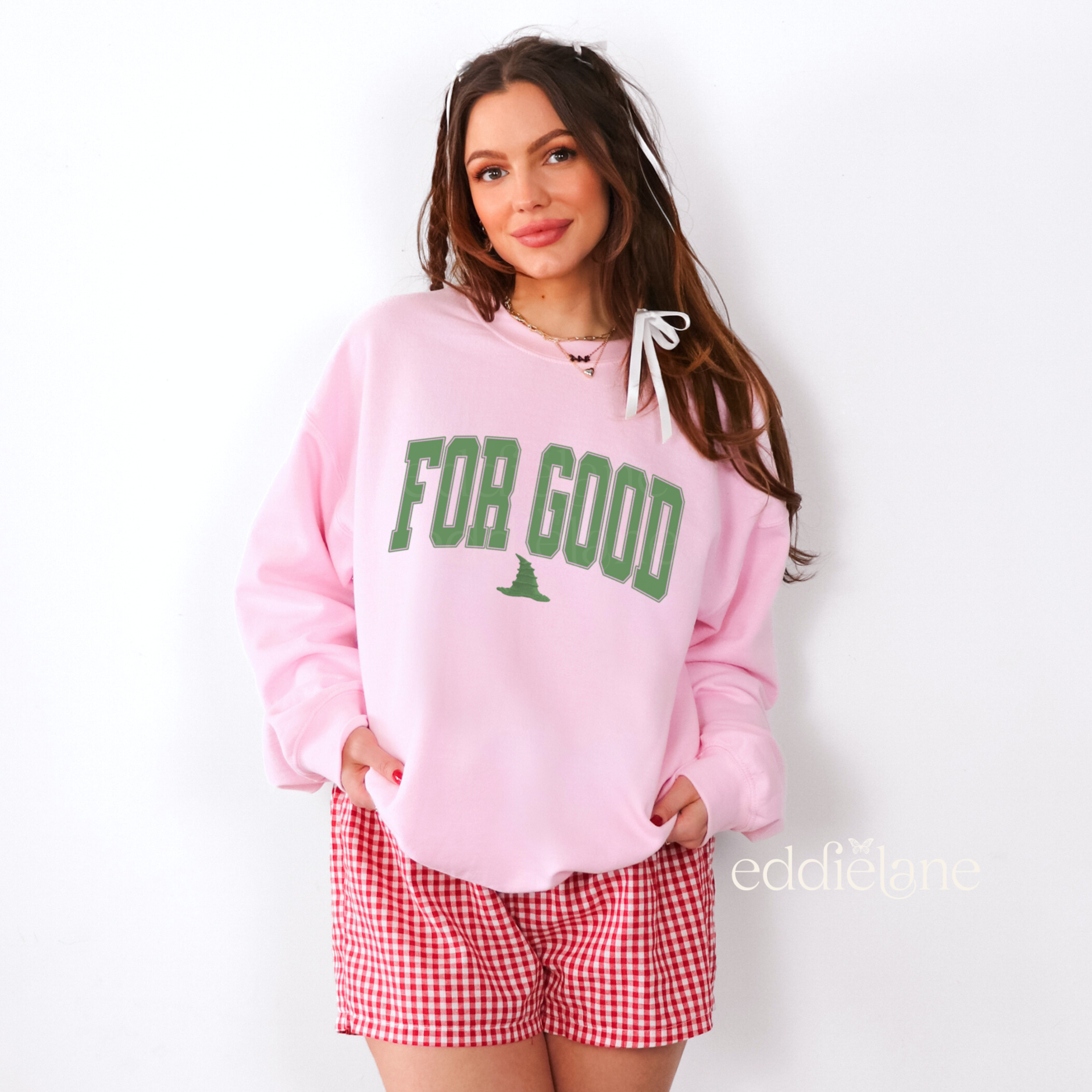 Woman wearing a pink sweatshirt with the text 'FOR GOOD' in a collegiate font.