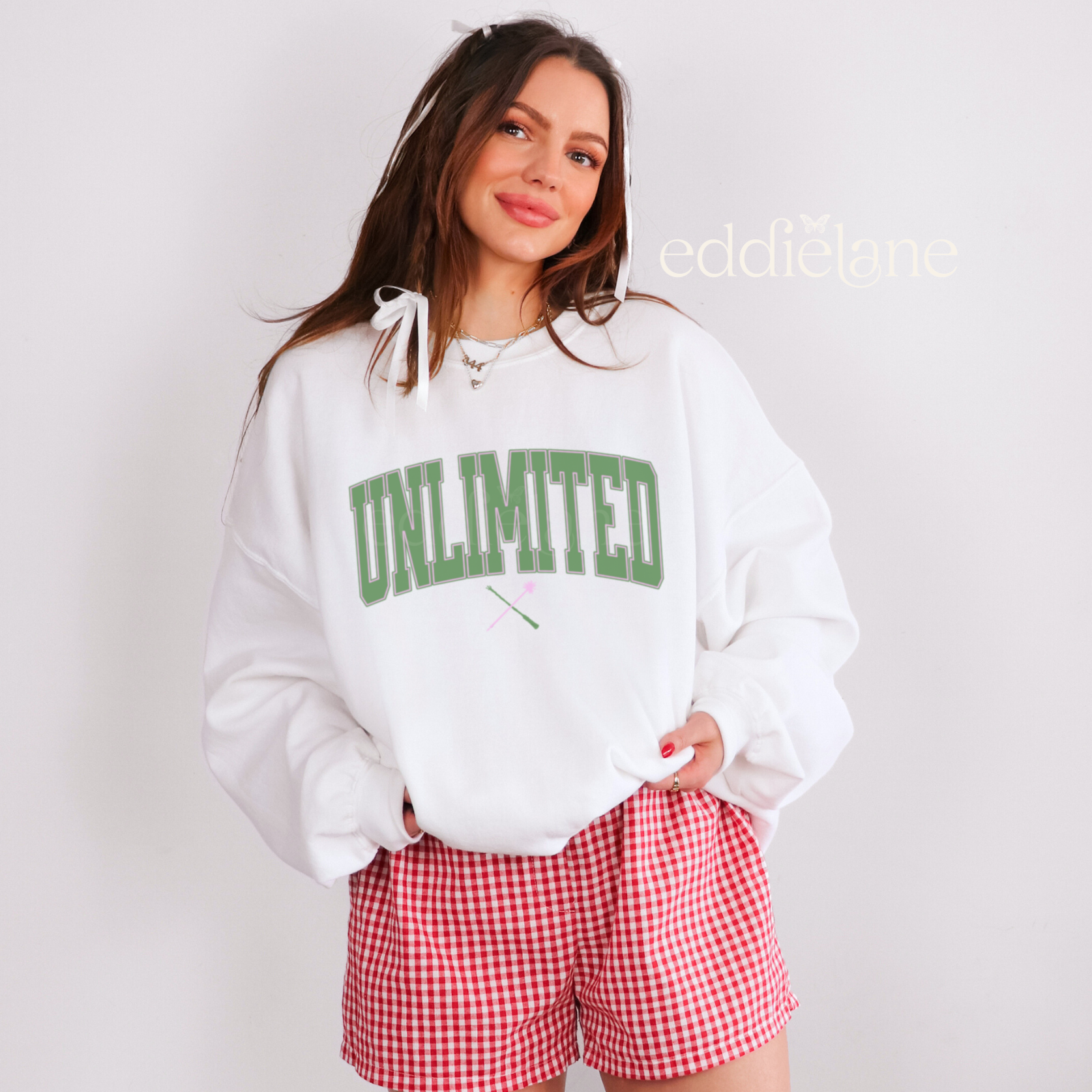Woman wearing a white sweatshirt with 'UNLIMITED' text in a collegiate font.