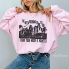Woman wearing a pink sweatshirt with a graphic design of haunted mansion and text "i think your house is haunted".