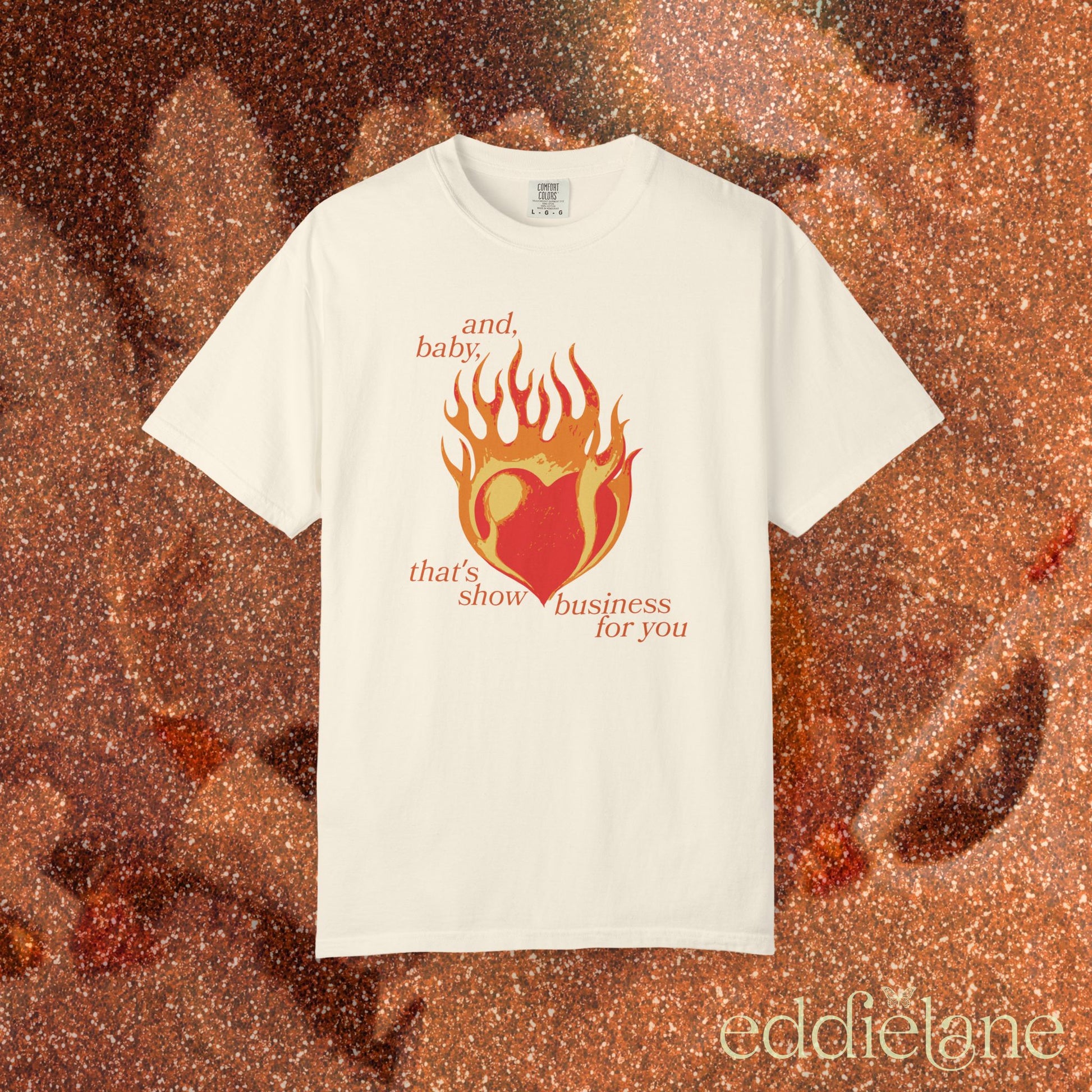 an ivory t-shirt with a heart in flames graphic and the words "and, baby, that's show business for you" inspired by taylor swift.
heart on fire ivory