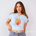 woman wearing a blue baby tee with a graphic of a heart on fire and the words "and, baby, that's show business for you"