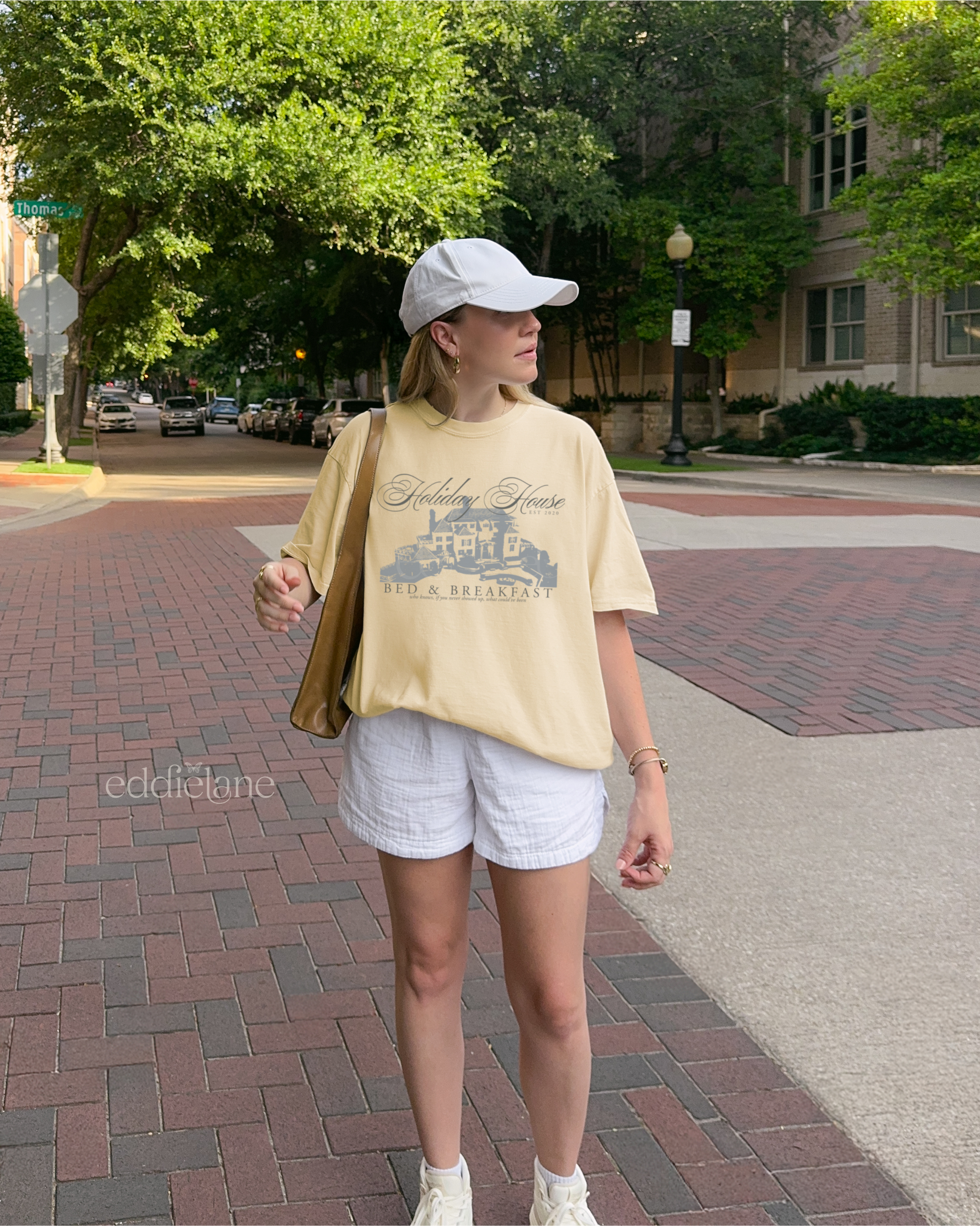 Girl wearing a yellow graphic t-shirt with 'Holiday House Bed & Breakfast' design, inspired by the last great american dynasty from folklore by taylor swift.