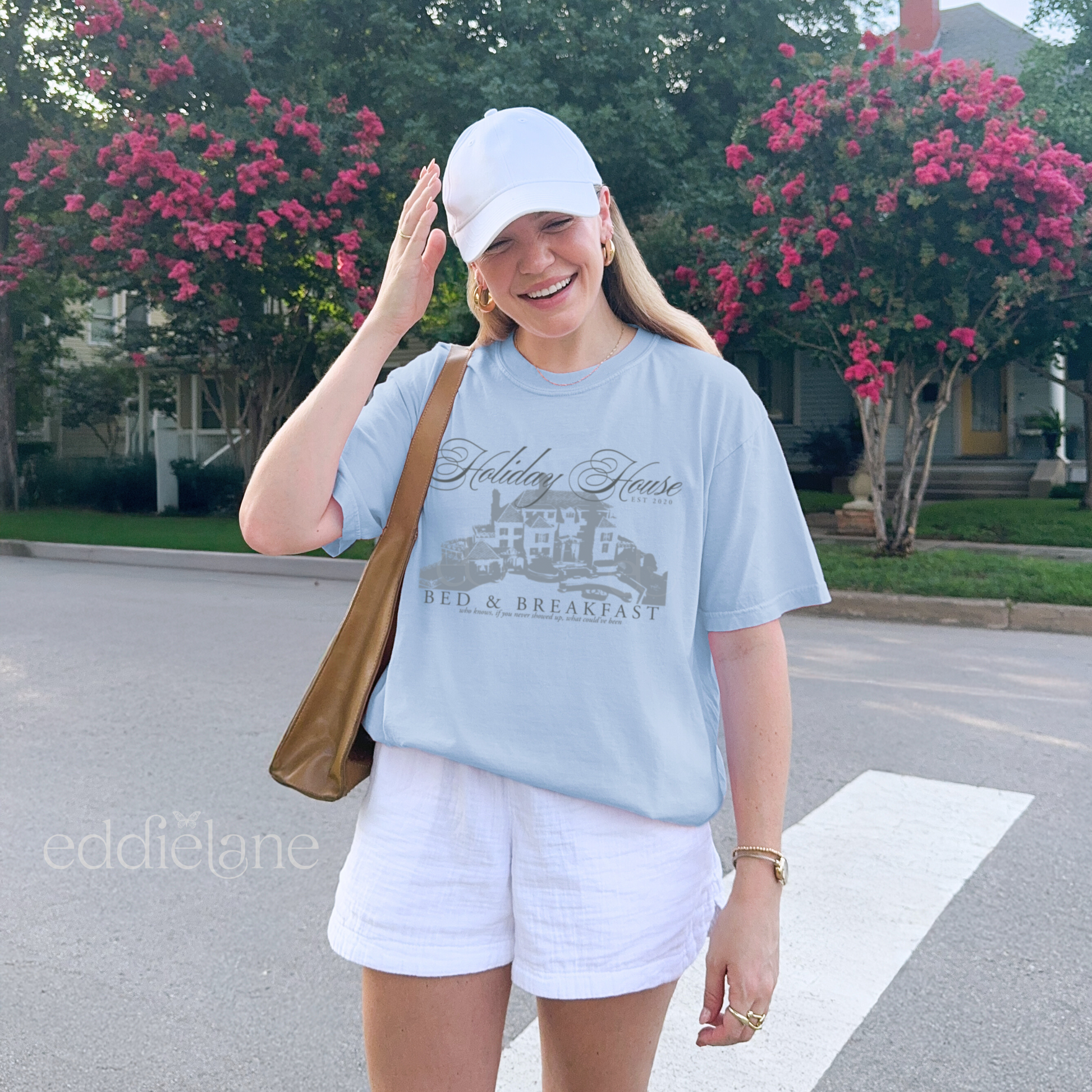 Girl wearing a light blue graphic t-shirt with 'Holiday House Bed & Breakfast' design, inspired by the last great american dynasty from folklore by taylor swift.
