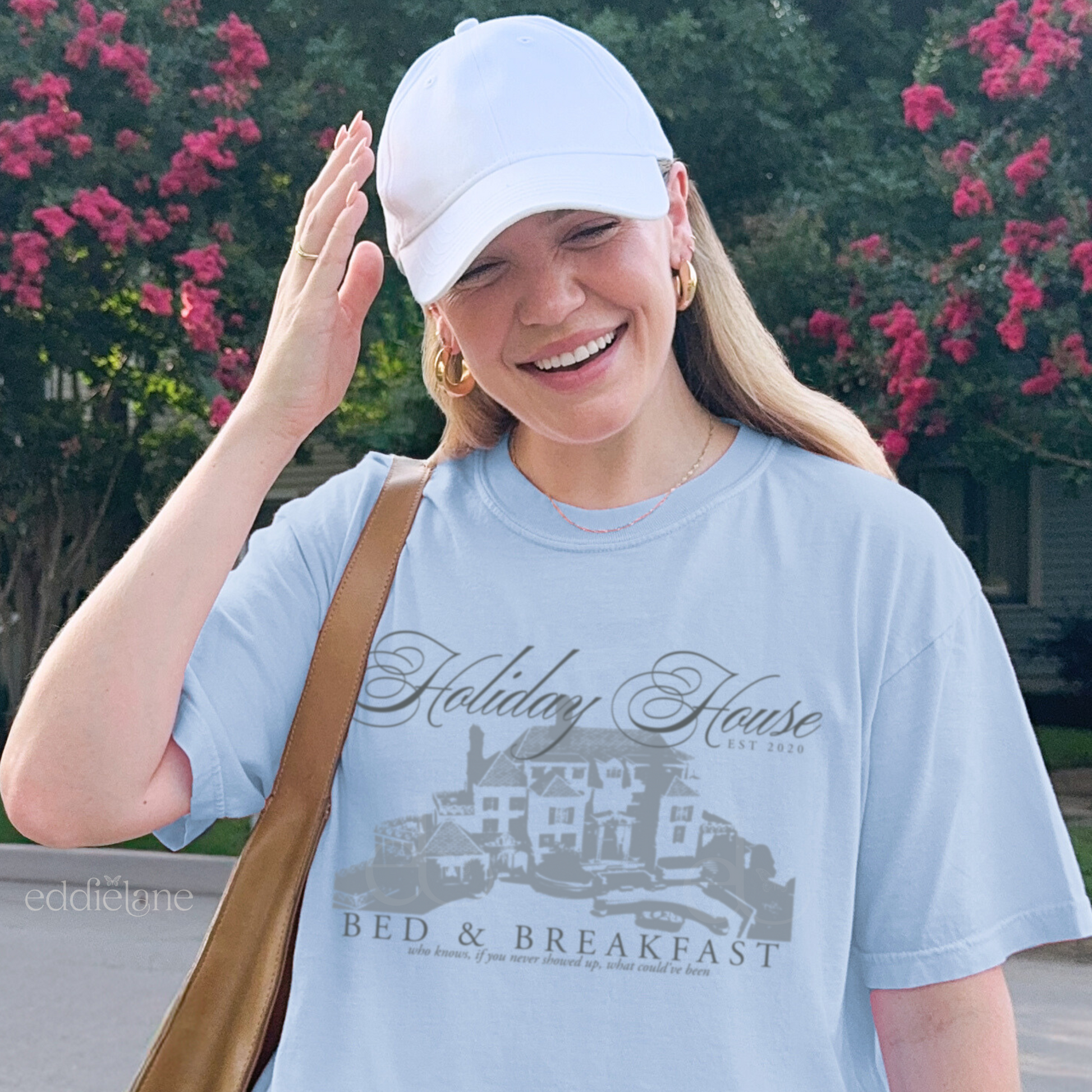 Girl wearing a light blue graphic t-shirt with 'Holiday House Bed & Breakfast' design, inspired by the last great american dynasty from folklore by taylor swift.