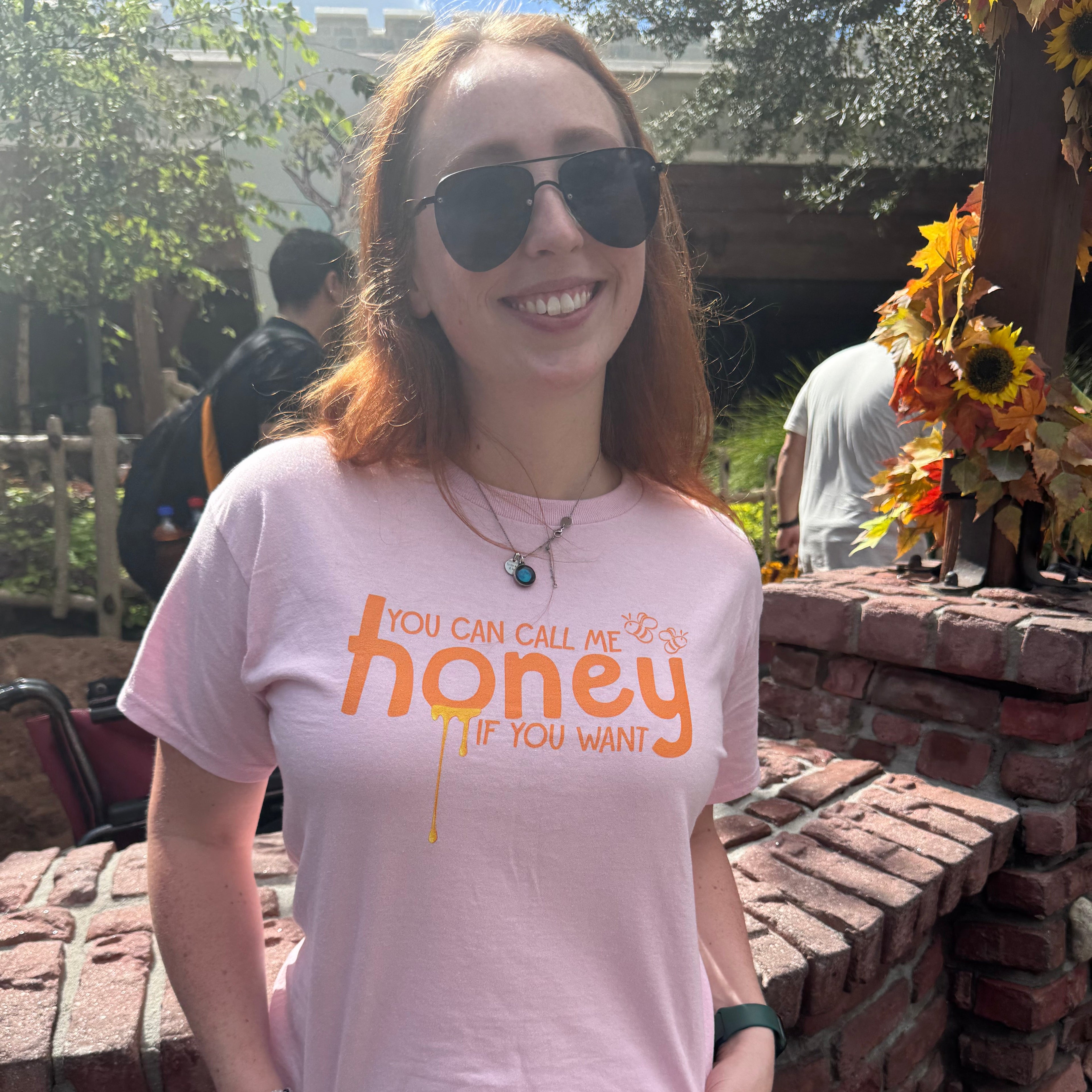 Woman wearing a pink t-shirt with the words "you can call me honey if you want"