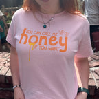 Woman wearing a pink t-shirt with the words "you can call me honey if you want"