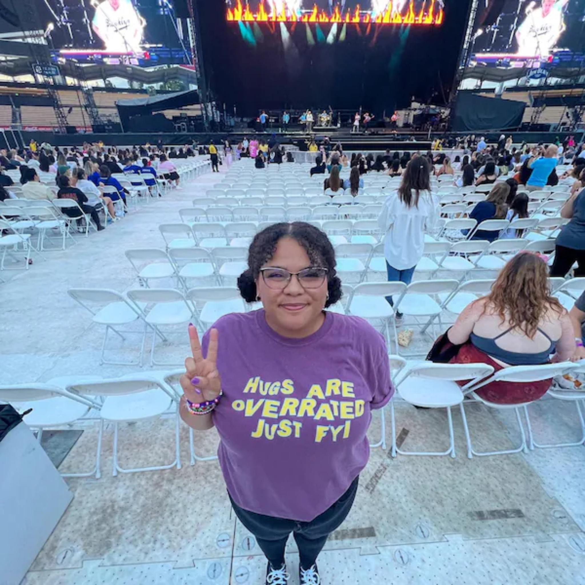 A woman in a berry-colored comfort colors oversized t-shirt that says "hugs are overrated just fyi" 