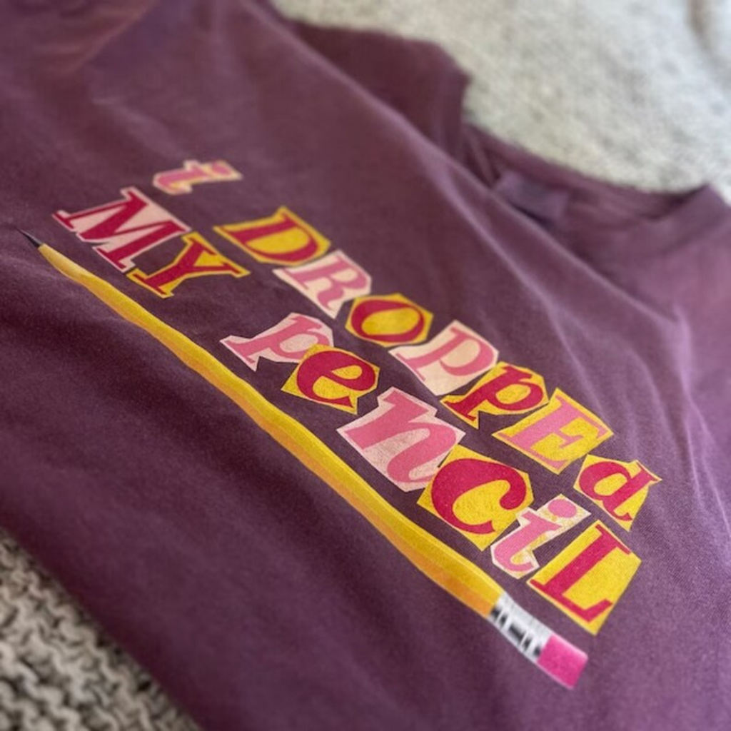 A berry colored t-shirt that says "i dropped my pencil" 