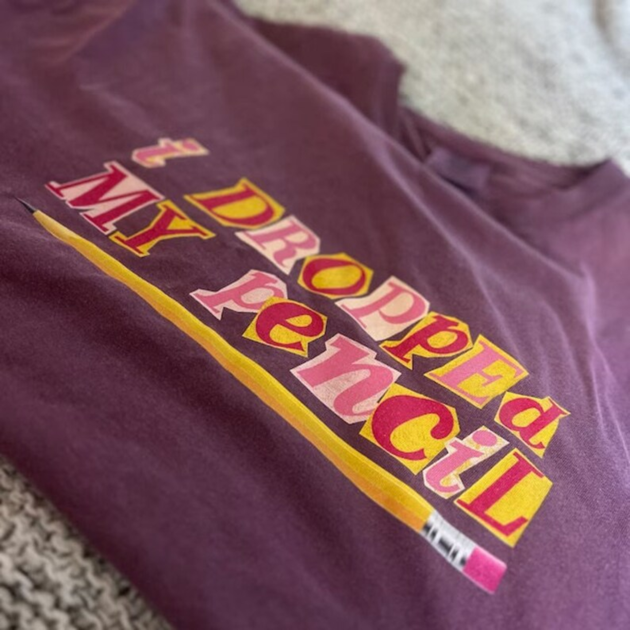 A berry colored t-shirt that says "i dropped my pencil" 