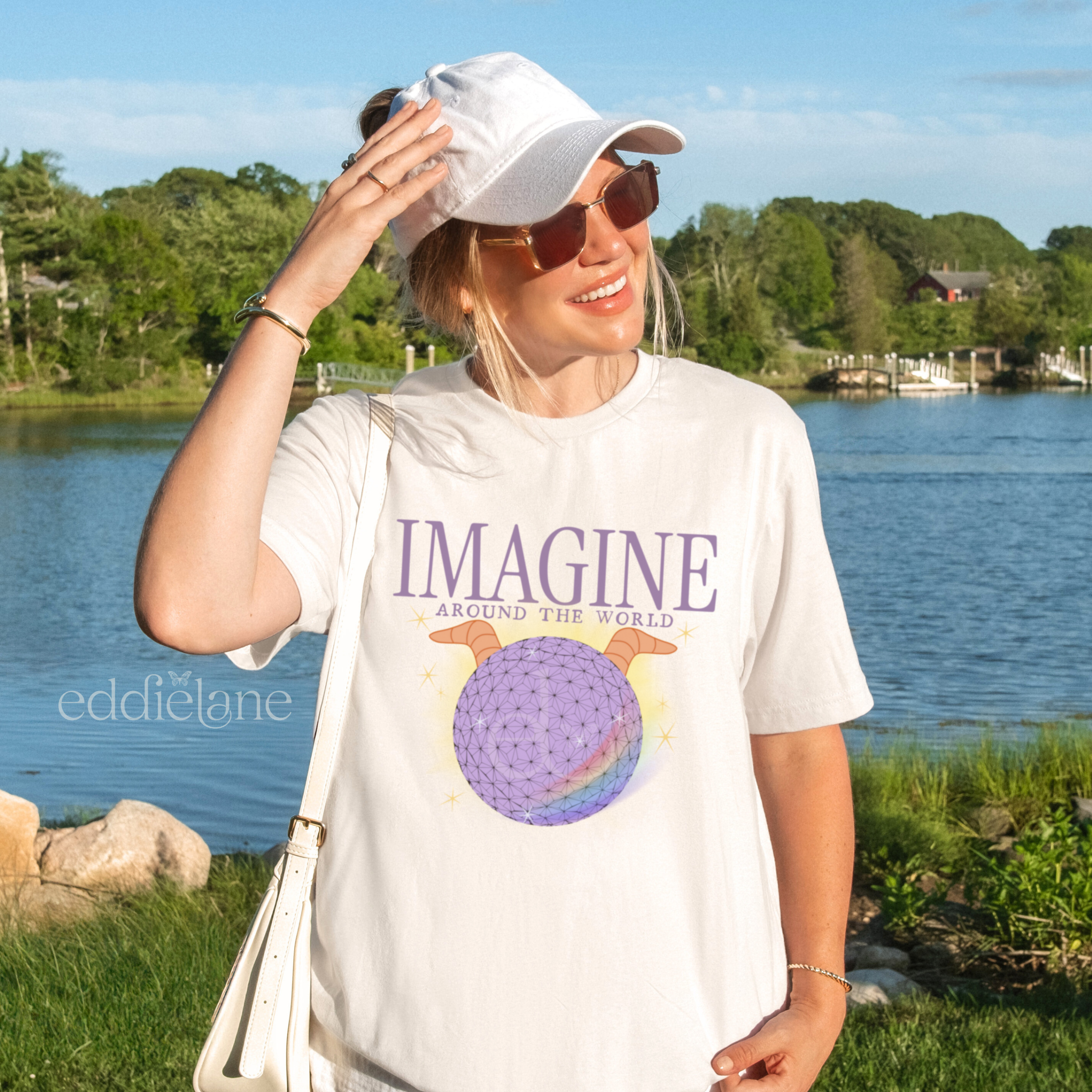 Woman wearing a 'Imagine Around the World' white comfort colors tshirt with a graphic of a figment inspired epcot ball