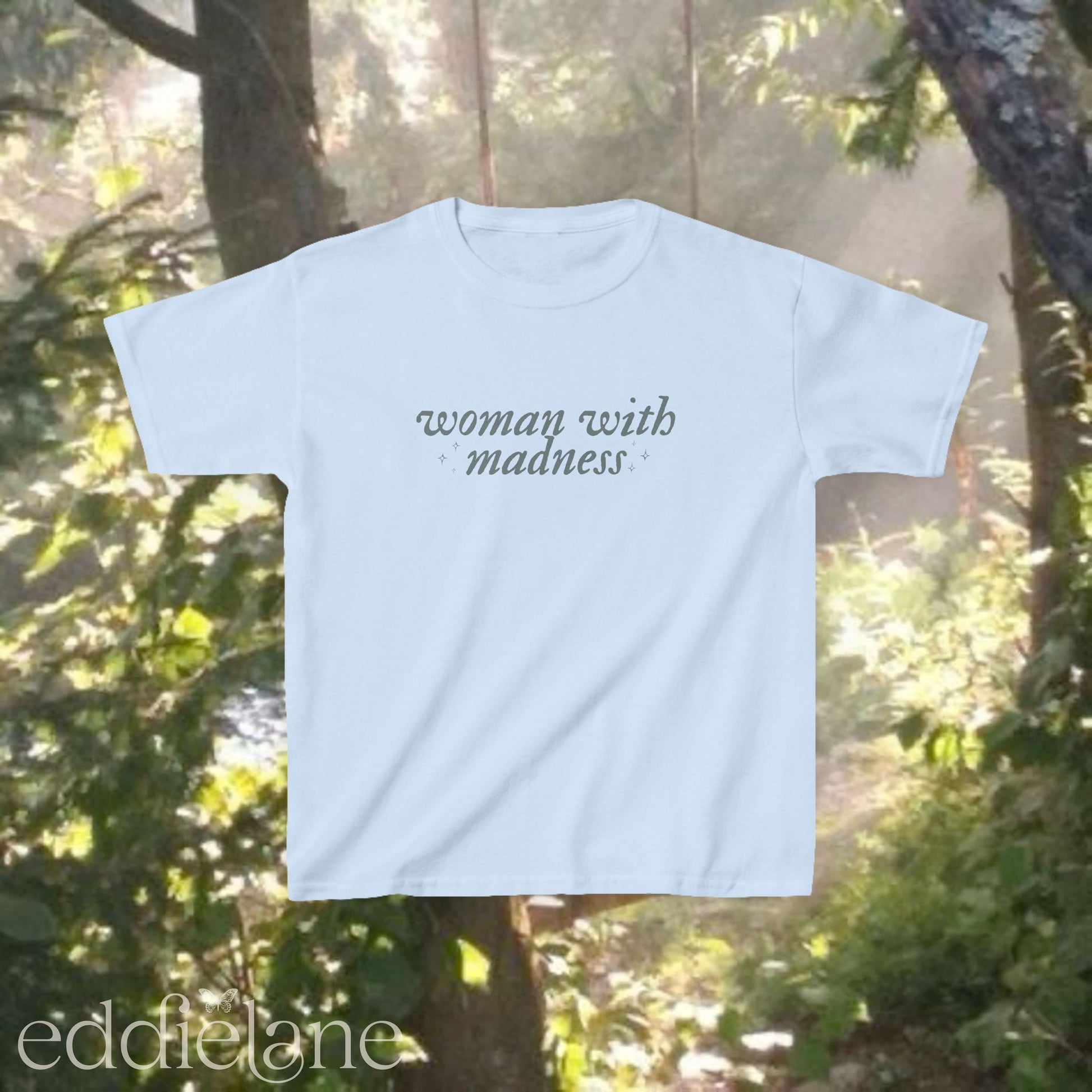 Light blue baby tee with words "woman with madness" inspired by the last great american dynasty from folklore by taylor swift.