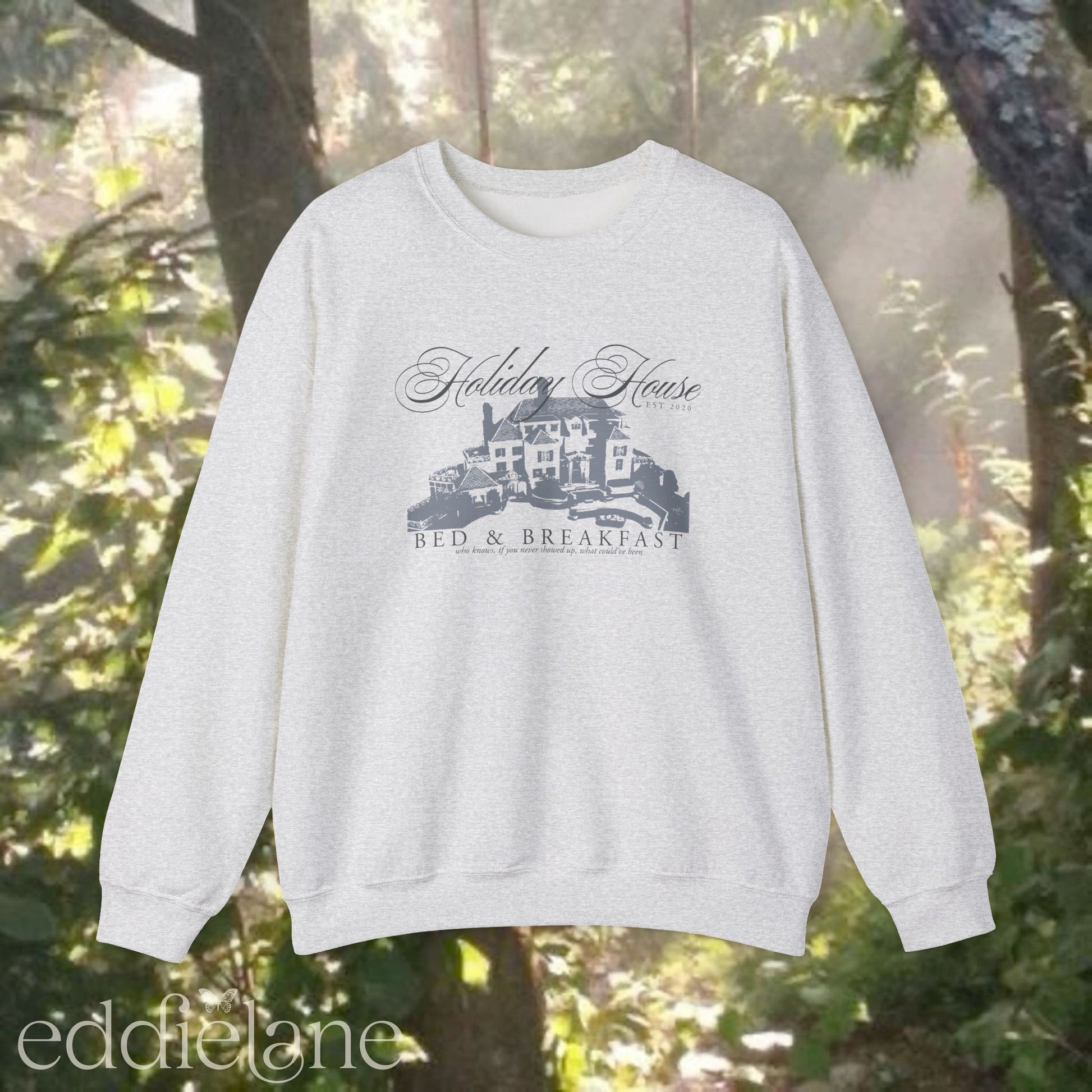 light gray crewneck sweatshirt that says "Holiday House Bed and Breakfast" with a silhouette of the holiday house from taylor swift's the last great american dynasty from folklore.
light gray swiftie sweatshirt holiday house