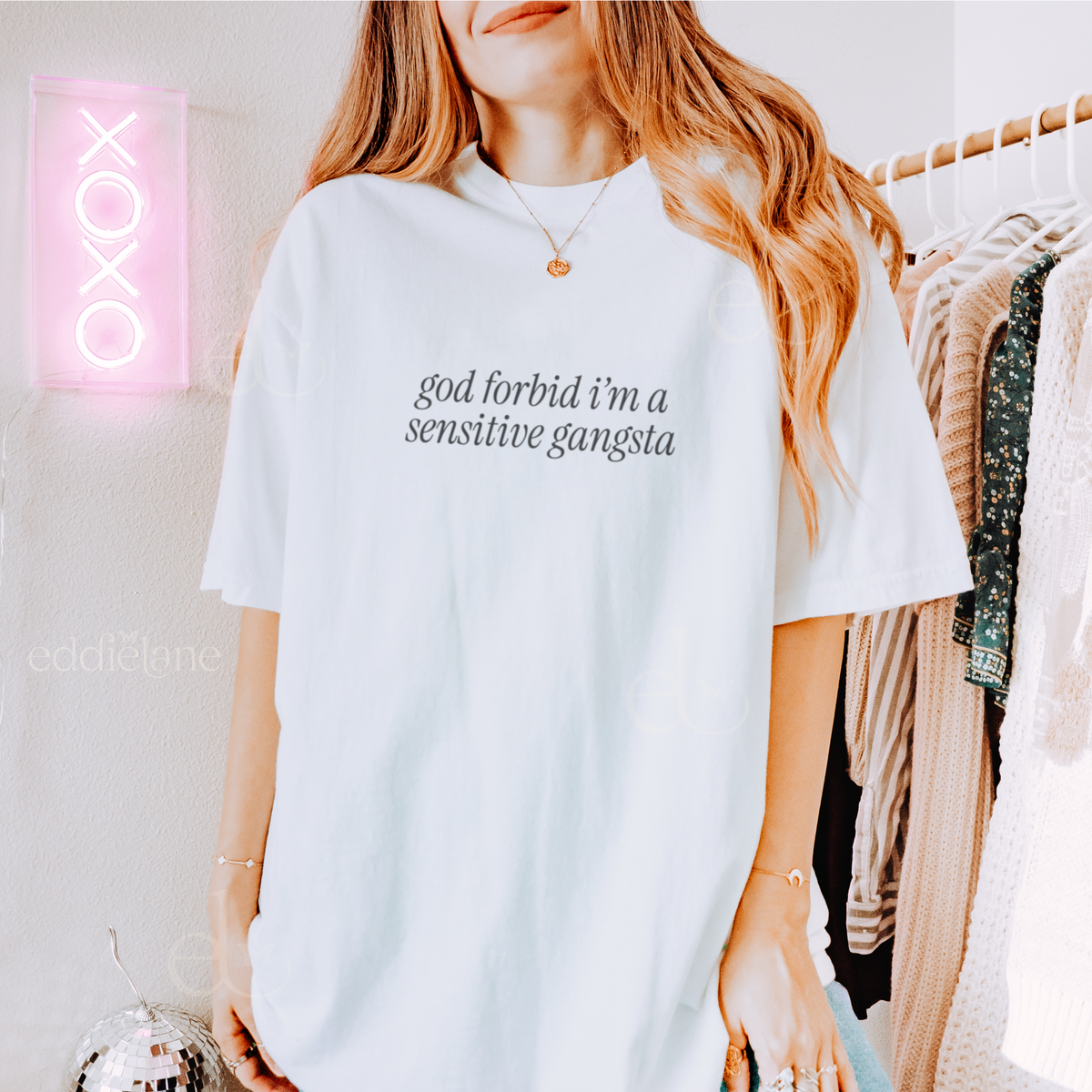 Woman wearing a white oversized tee that says "god forbid i'm a sensitive gangsta" inspired by amaya from love island usa.