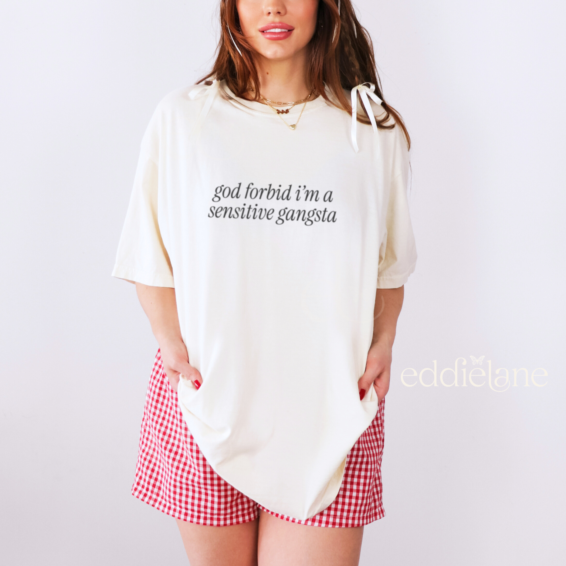 Woman wearing a white oversized tee that says "god forbid i'm a sensitive gangsta" inspired by amaya from love island usa.