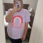 Woman wearing a light purple graphic t-shirt with a rainbow design and text that says "ooh wee I love the jonas brothers" 