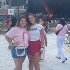 Woman wearing a light pink graphic t-shirt with a rainbow design and text that says "ooh wee I love the jonas brothers" 