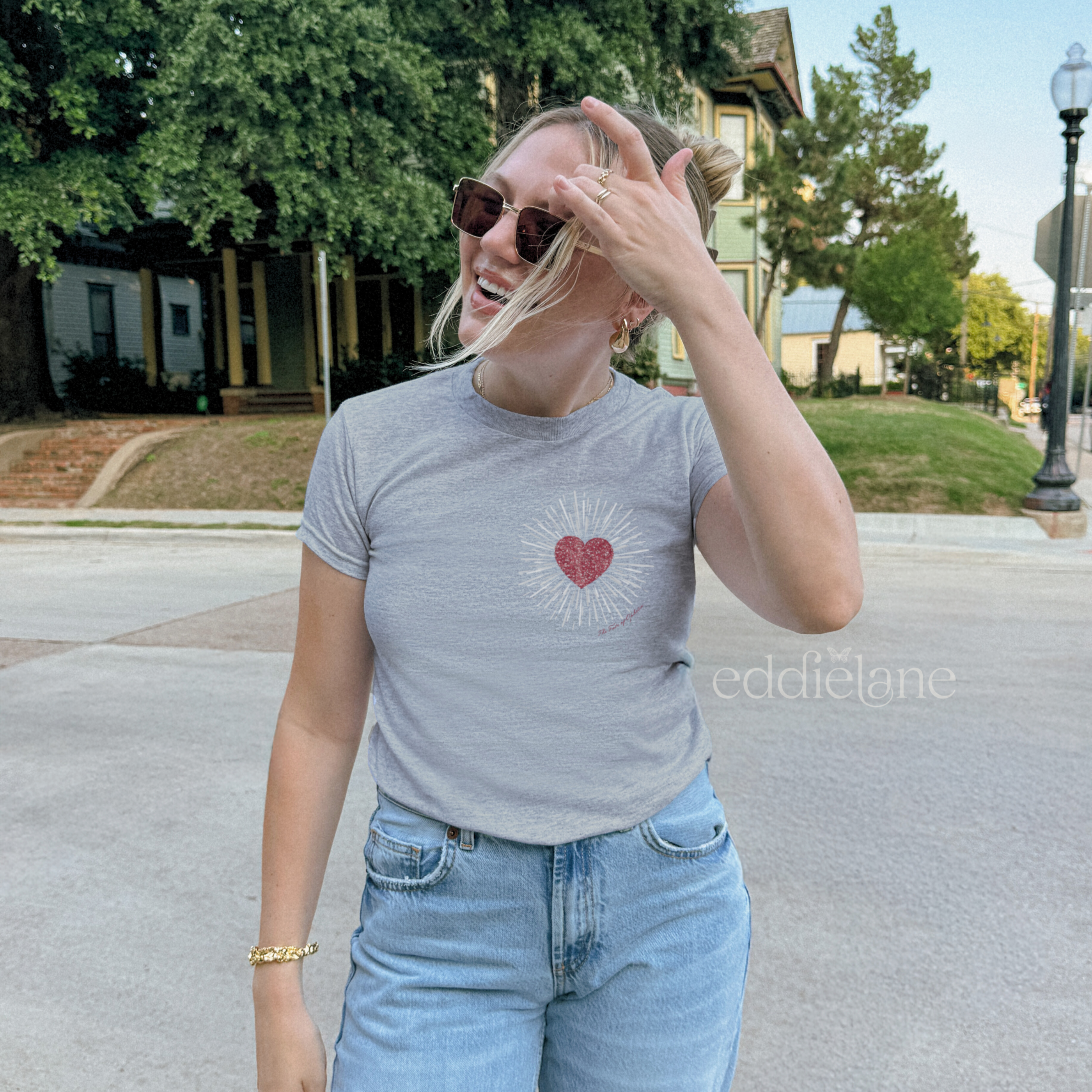 Woman wearing a gray baby tee with a heart design inspired by the dress from the fate of ophelia